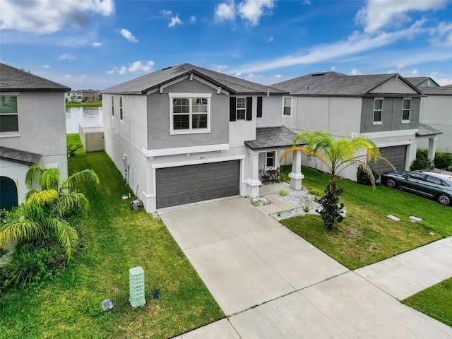 view of front of property with a front yard, a garage, and a water view