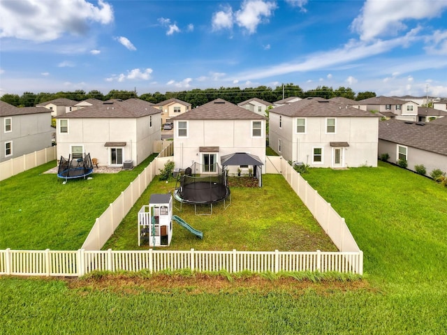 back of house featuring a lawn and a trampoline