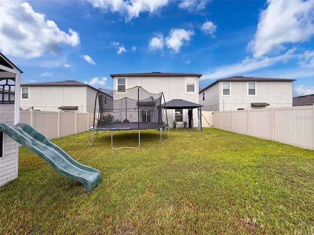 exterior space with a trampoline, a playground, a lawn, and a gazebo