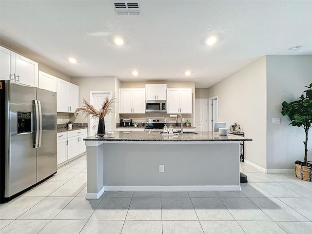 kitchen featuring an island with sink, stainless steel appliances, and white cabinets