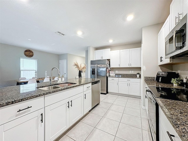 kitchen with dark stone countertops, sink, appliances with stainless steel finishes, and white cabinets