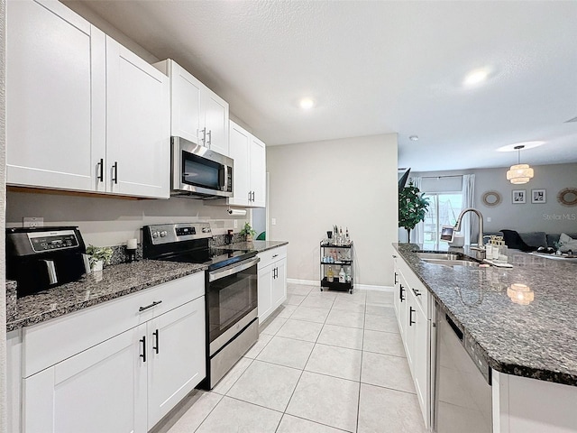 kitchen featuring white cabinets, stainless steel appliances, sink, light tile patterned flooring, and pendant lighting