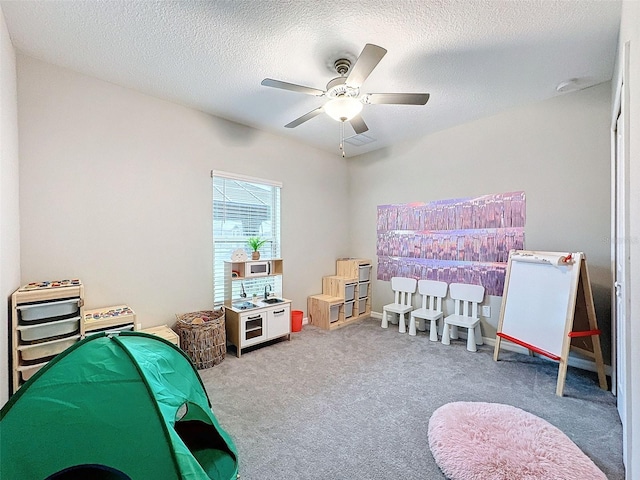 game room featuring ceiling fan, carpet, and a textured ceiling