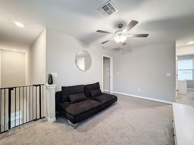 sitting room with a textured ceiling, light colored carpet, and ceiling fan