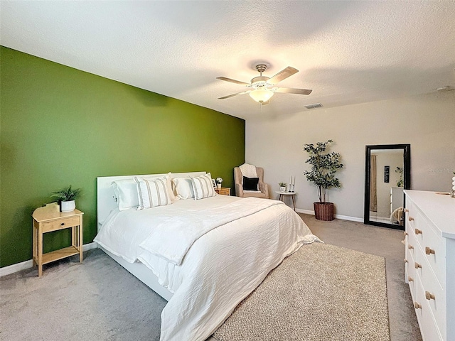 carpeted bedroom featuring ceiling fan and a textured ceiling