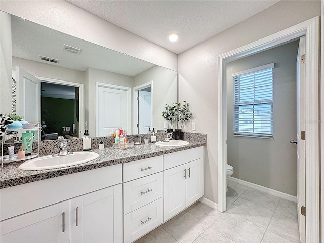 bathroom with tile patterned flooring, toilet, a textured ceiling, and vanity