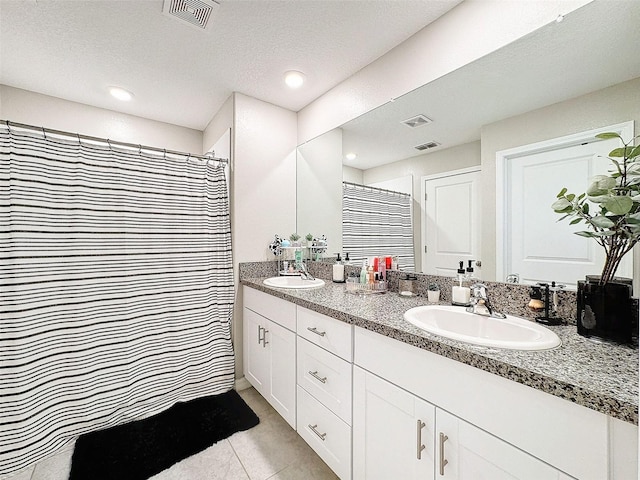 bathroom featuring a textured ceiling, vanity, walk in shower, and tile patterned flooring