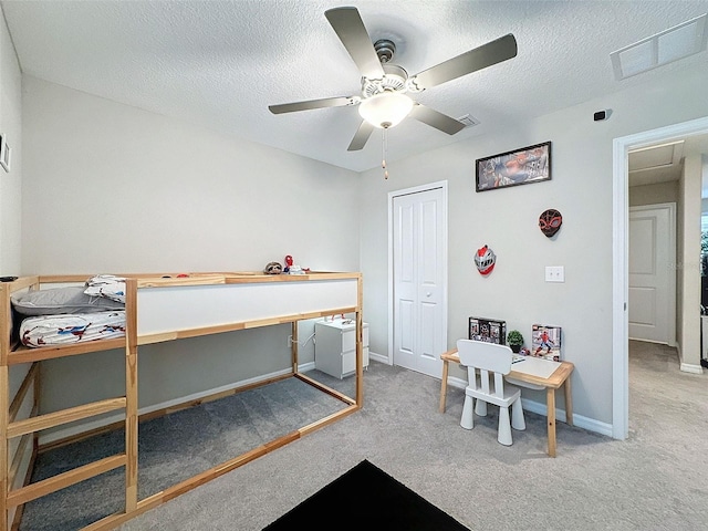 carpeted bedroom featuring a textured ceiling, ceiling fan, and a closet