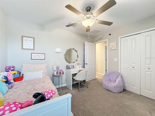 bedroom with a closet, ceiling fan, light colored carpet, and a textured ceiling