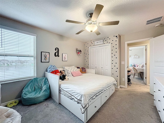 bedroom featuring carpet flooring, a textured ceiling, ceiling fan, and a closet