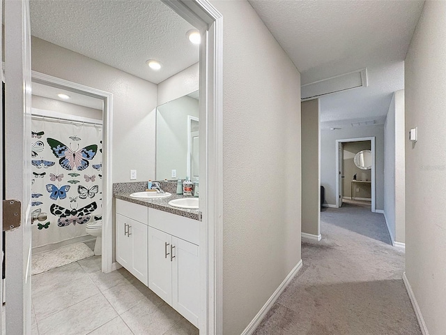 bathroom featuring toilet, tile patterned flooring, vanity, a textured ceiling, and a shower with curtain