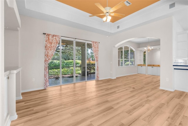 unfurnished living room featuring ornamental molding, light hardwood / wood-style flooring, a raised ceiling, and ceiling fan with notable chandelier