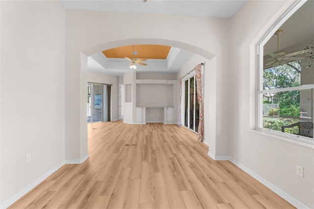 corridor featuring light wood-type flooring and a tray ceiling