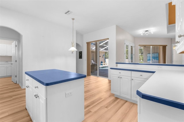 kitchen featuring decorative light fixtures, a kitchen island, white cabinetry, and light hardwood / wood-style flooring