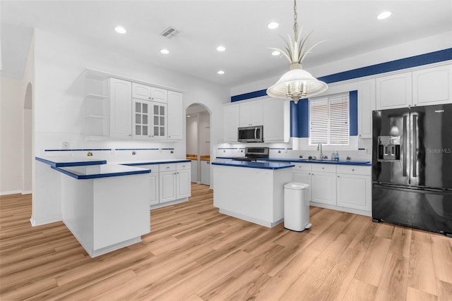 kitchen featuring appliances with stainless steel finishes, light hardwood / wood-style floors, a center island, hanging light fixtures, and white cabinets