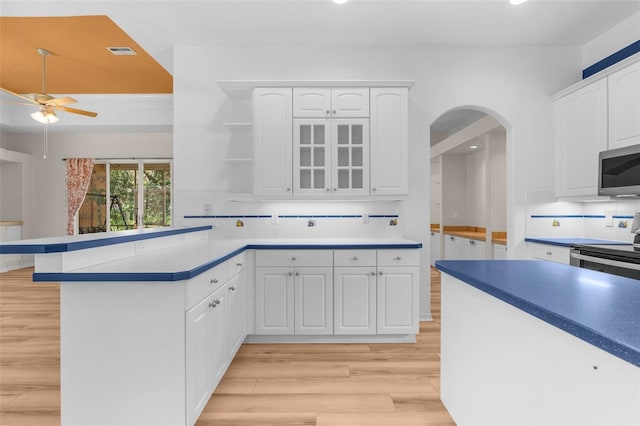 kitchen featuring white cabinets, light hardwood / wood-style flooring, appliances with stainless steel finishes, ceiling fan, and decorative backsplash