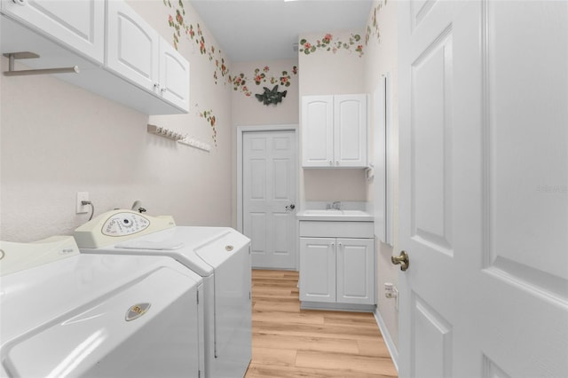 washroom with cabinets, sink, independent washer and dryer, and light wood-type flooring