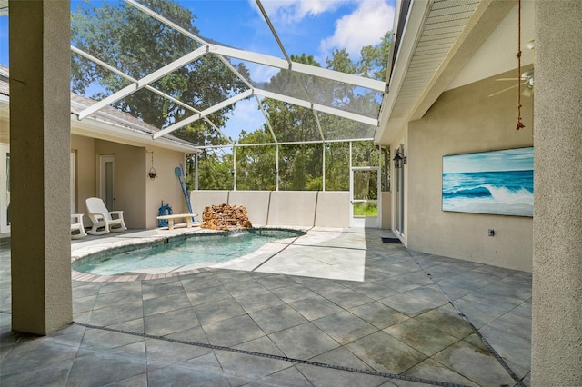 view of pool featuring glass enclosure, pool water feature, ceiling fan, and a patio