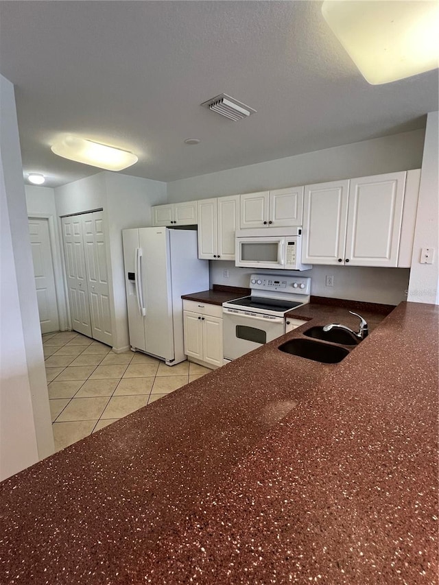 kitchen featuring white appliances, light tile patterned floors, white cabinetry, and sink