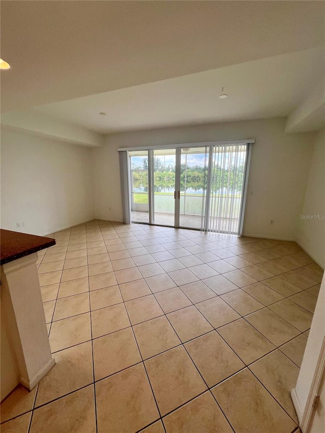 empty room with light tile patterned flooring and a healthy amount of sunlight