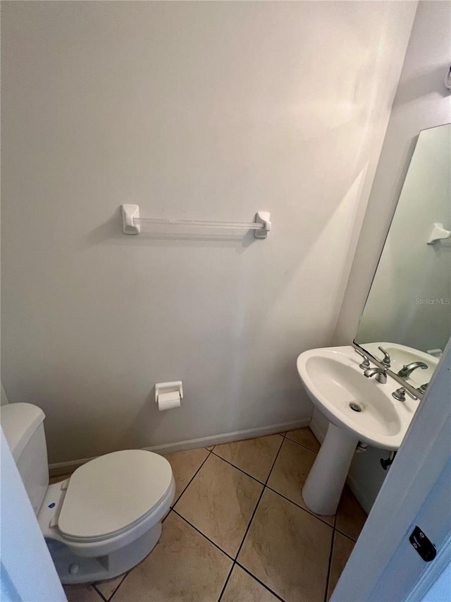 bathroom with toilet, sink, and tile patterned floors