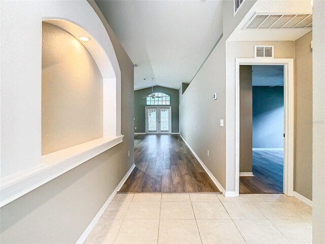 hall with light wood-type flooring, vaulted ceiling, and french doors