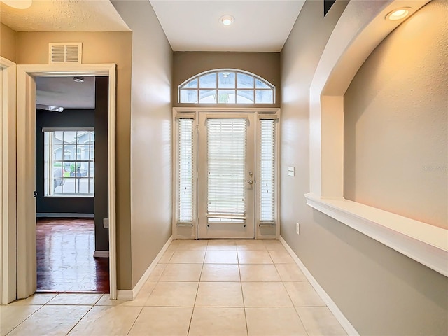 foyer featuring a healthy amount of sunlight, light tile patterned floors, and visible vents