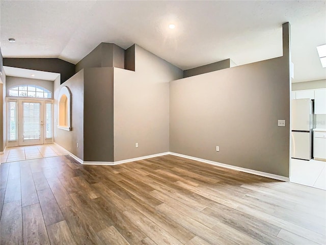 entrance foyer featuring vaulted ceiling, light wood-style flooring, and baseboards