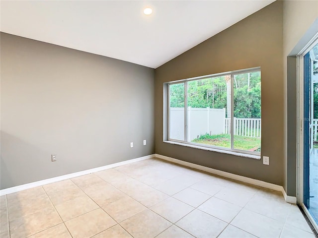 empty room featuring lofted ceiling, baseboards, and light tile patterned floors