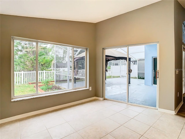 empty room with baseboards, a wealth of natural light, and light tile patterned flooring