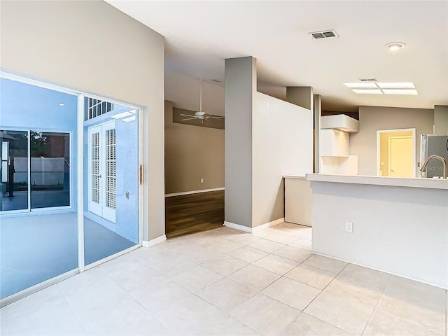 spare room with light tile patterned floors, baseboards, visible vents, and a ceiling fan