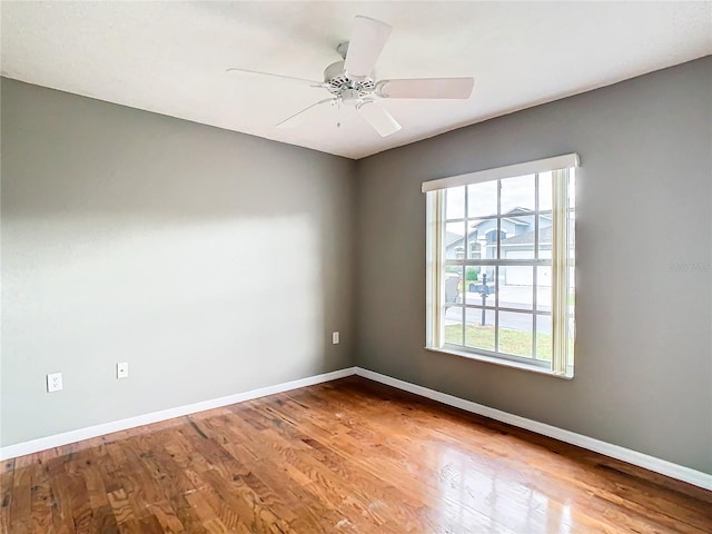 empty room with wood finished floors, a ceiling fan, and baseboards