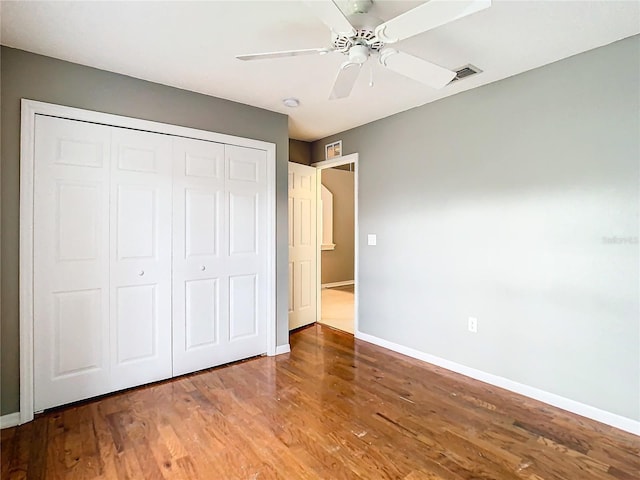 unfurnished bedroom with baseboards, a closet, visible vents, and wood finished floors