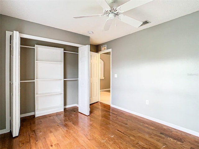 unfurnished bedroom featuring a closet, visible vents, baseboards, and wood finished floors