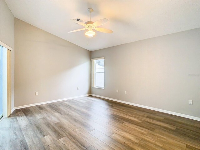 empty room with dark wood-style floors, baseboards, and a ceiling fan