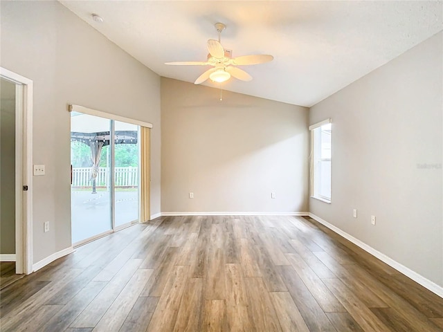 spare room with vaulted ceiling, wood finished floors, and baseboards