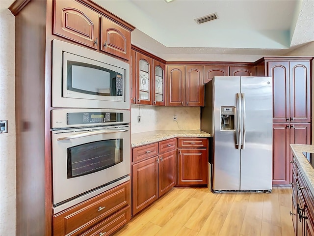 kitchen with light stone countertops, light hardwood / wood-style flooring, and stainless steel appliances