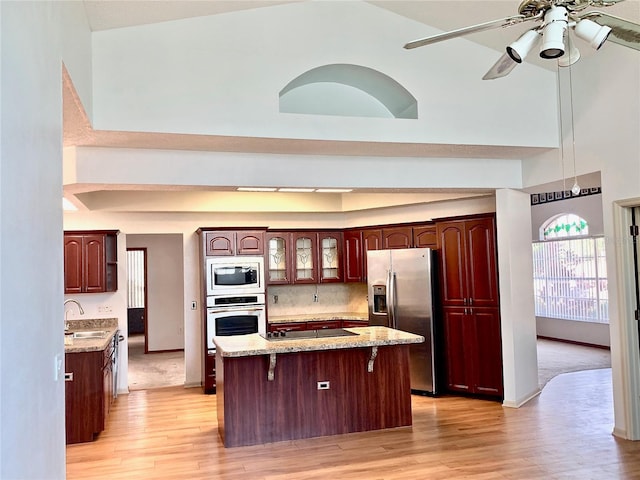 kitchen featuring sink, a breakfast bar, appliances with stainless steel finishes, a towering ceiling, and a center island