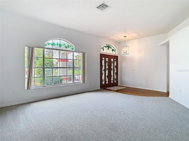 carpeted empty room with a chandelier, visible vents, and baseboards