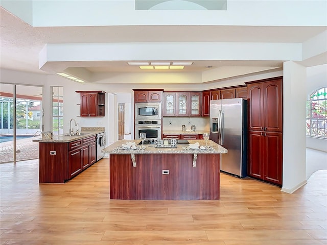 kitchen with a breakfast bar area, light wood finished floors, appliances with stainless steel finishes, a sink, and a peninsula