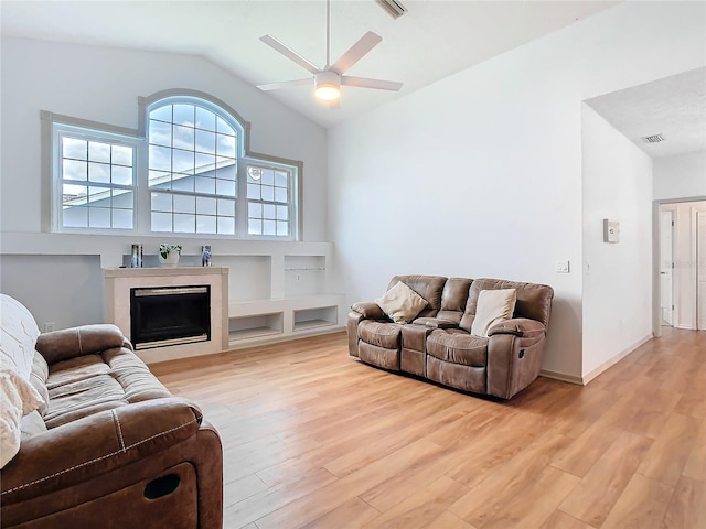 living room with visible vents, ceiling fan, vaulted ceiling, light wood-style floors, and a fireplace