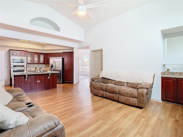 living room with light wood-style floors, high vaulted ceiling, and a ceiling fan