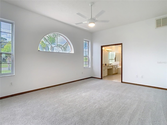 empty room with visible vents, ceiling fan, light carpet, and baseboards