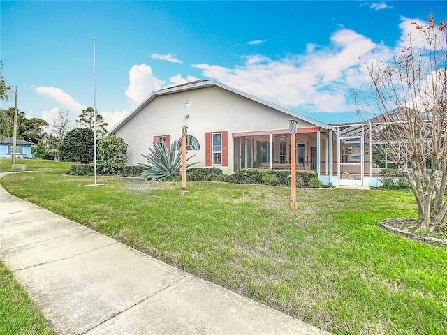 view of front facade with glass enclosure, a front yard, and stucco siding