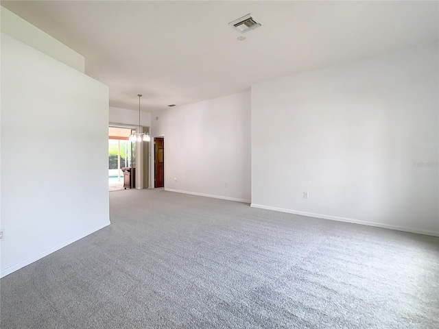 unfurnished room with a chandelier, carpet, visible vents, and baseboards