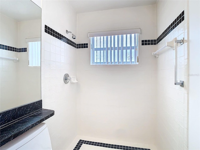 bathroom with a tile shower and toilet