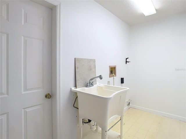 clothes washing area with washer hookup, laundry area, a sink, and baseboards