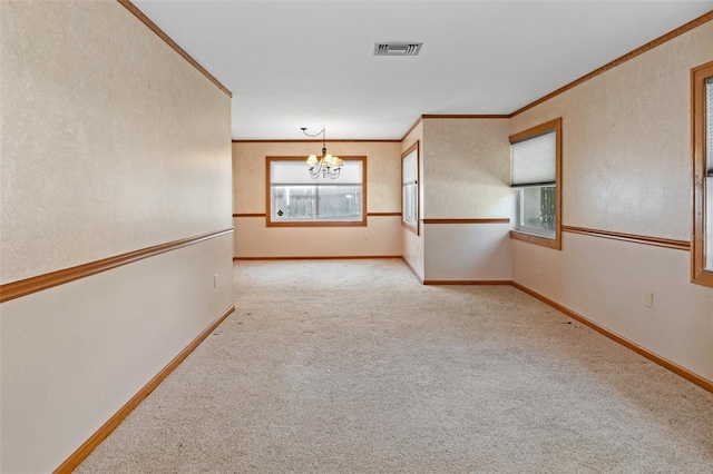 carpeted spare room with an inviting chandelier, baseboards, visible vents, and ornamental molding