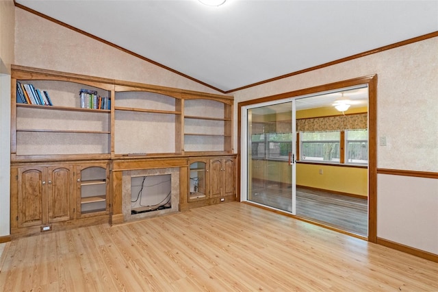 unfurnished living room featuring built in shelves, wood finished floors, crown molding, a fireplace, and vaulted ceiling