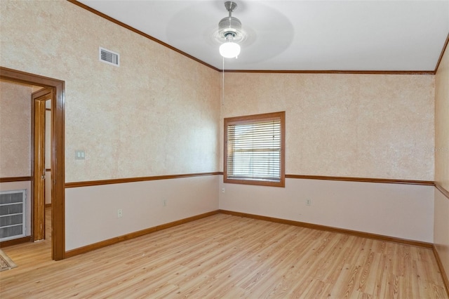 spare room with crown molding, wood finished floors, visible vents, and baseboards